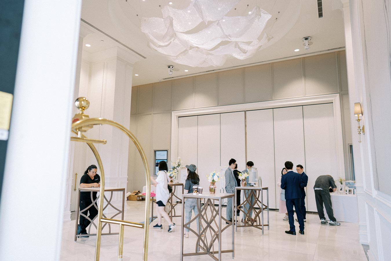 Elegant hotel interior with people socializing during an event, featuring modern decor, high ceilings, and stylish lighting.