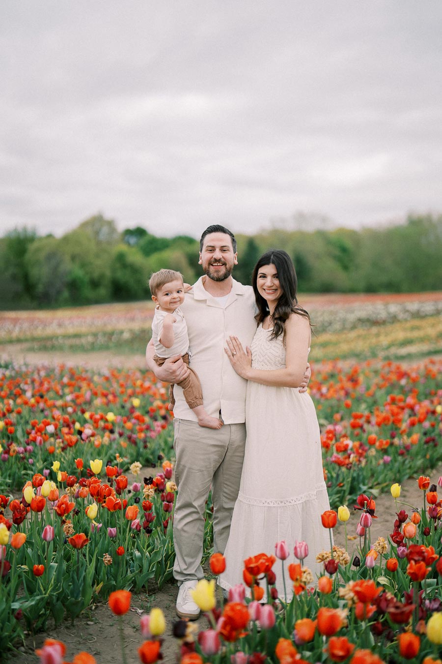 A family enjoys a day out in a vibrant tulip field, capturing a joyful moment together.