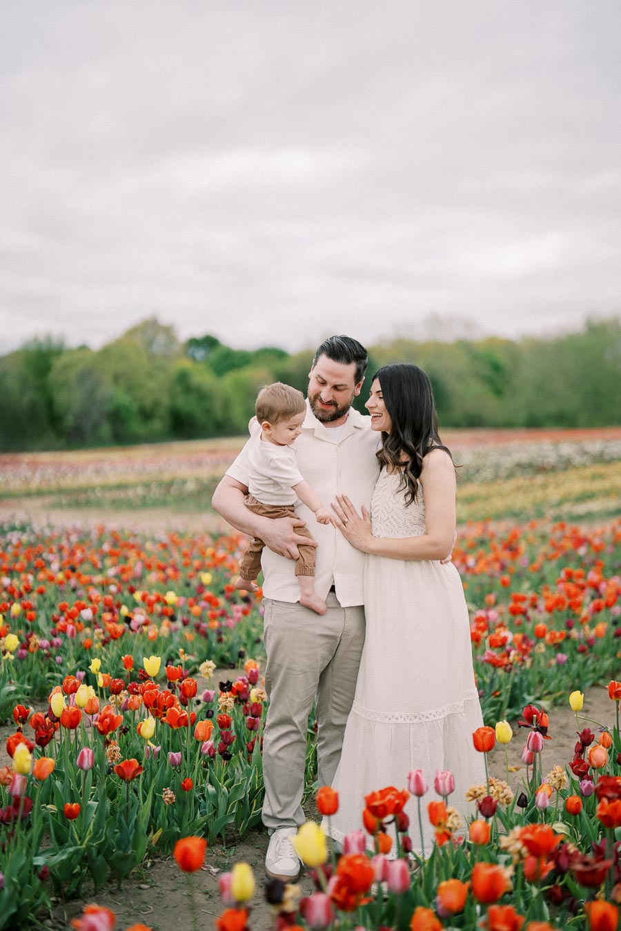 A family enjoys a day out in a vibrant tulip field, surrounded by colorful blooms.