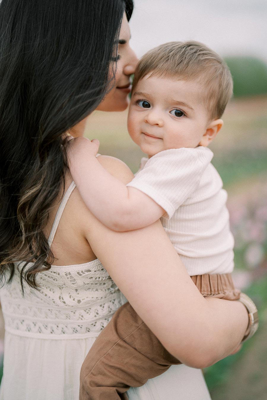 A tender moment between a woman and a baby in an outdoor setting, showcasing a close bond.