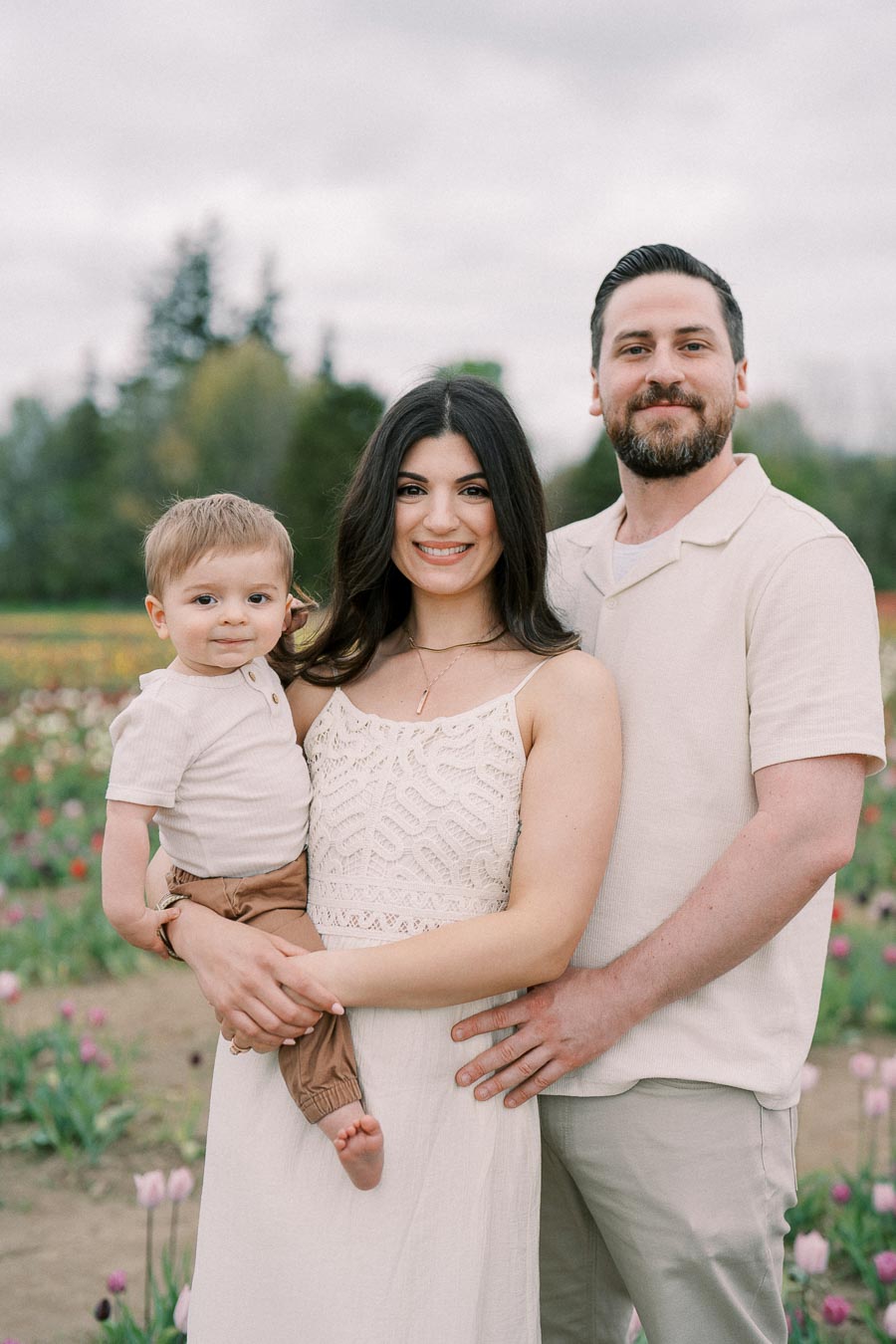 A family enjoying a day out in a tulip field, dressed in coordinating light-colored outfits.