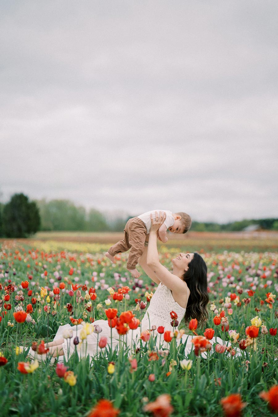 A joyful moment captured between a woman and a baby in a vibrant tulip field.
