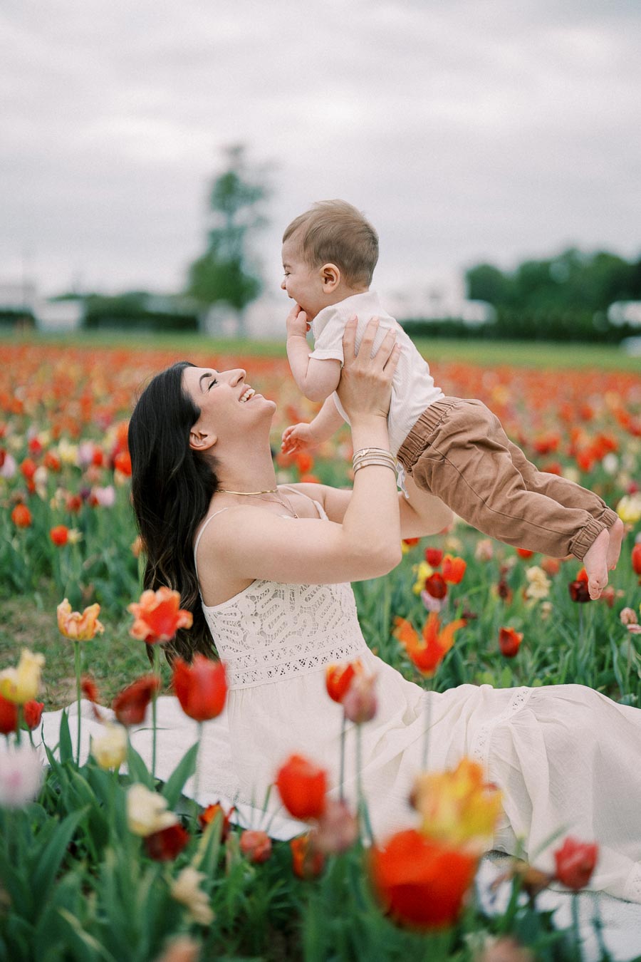 A joyful moment between a woman and a baby in a vibrant tulip field.