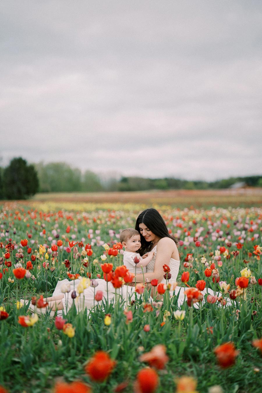 A woman and a child enjoying a moment together in a vibrant tulip field.
