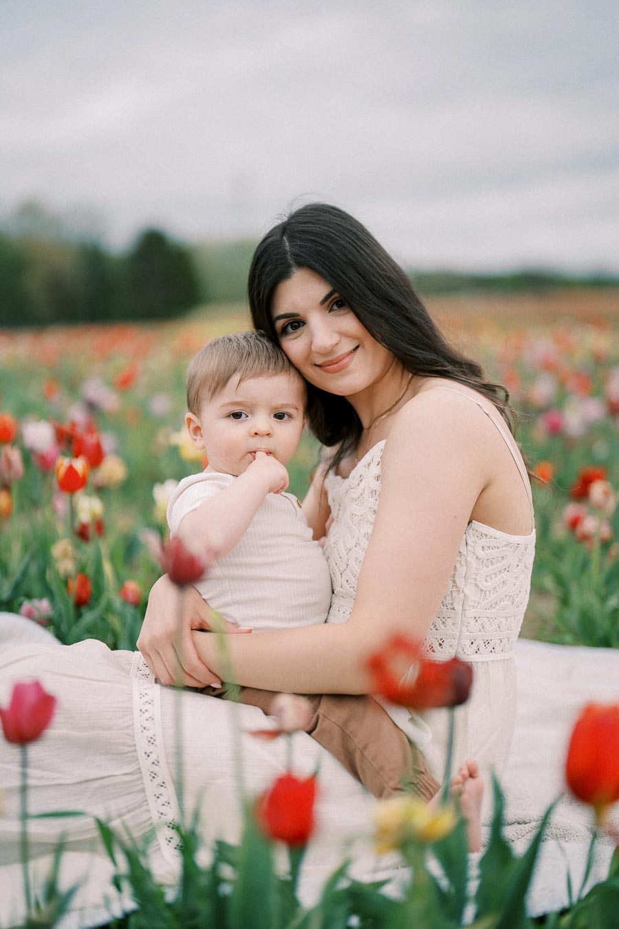 A woman and child sitting in a vibrant tulip field, enjoying a peaceful moment together.