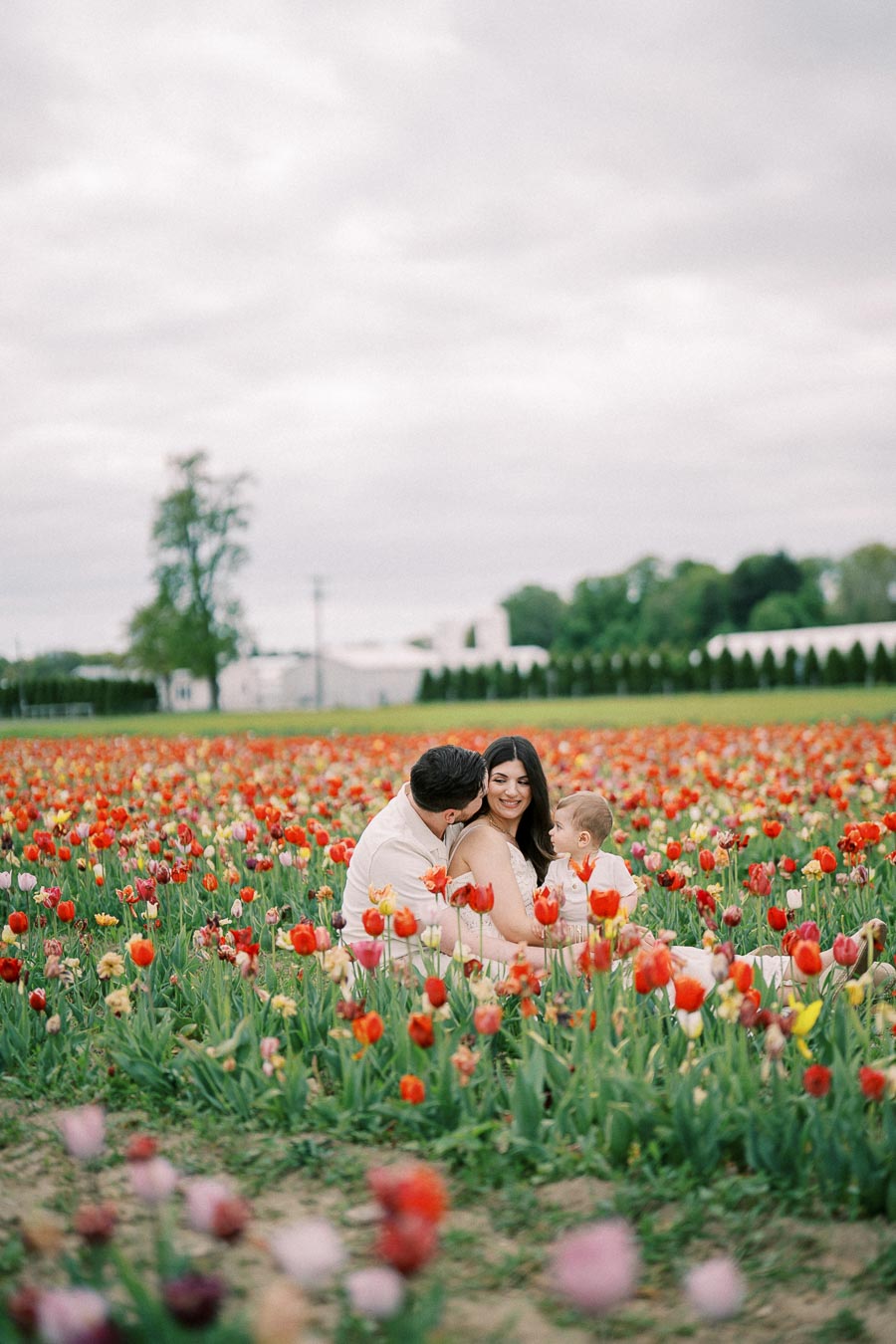 A family enjoys a day out in a vibrant tulip field, surrounded by colorful blooms.