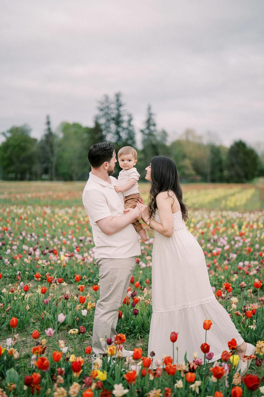 A family enjoys a day out in a vibrant tulip field, surrounded by colorful blooms and lush greenery.