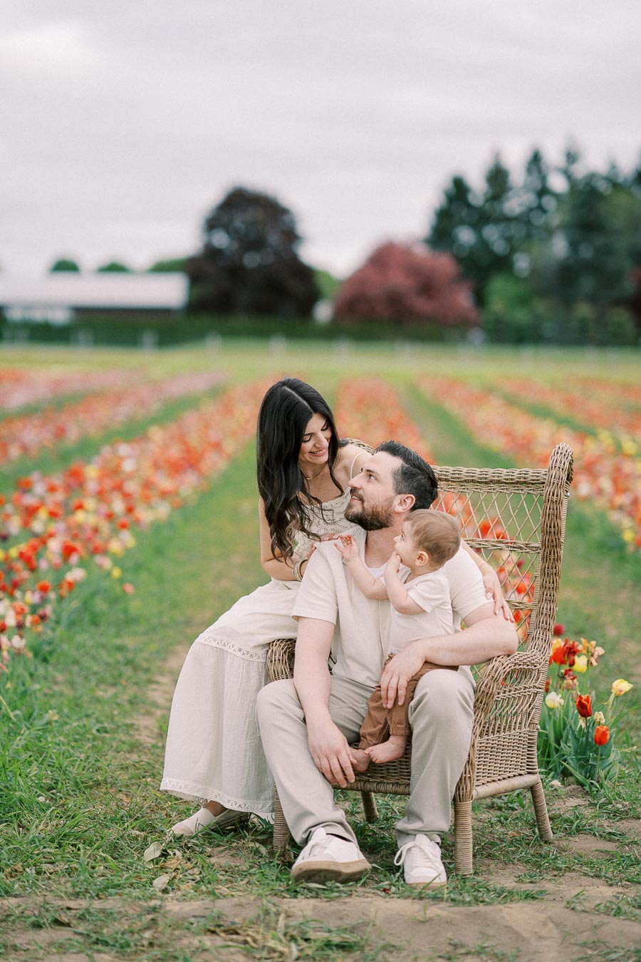 A family enjoys a moment together in a vibrant tulip field, surrounded by rows of colorful flowers.