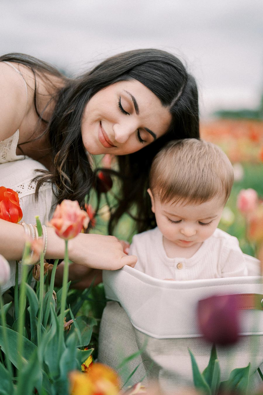A tender moment captured between a woman and a baby amidst a vibrant field of tulips.