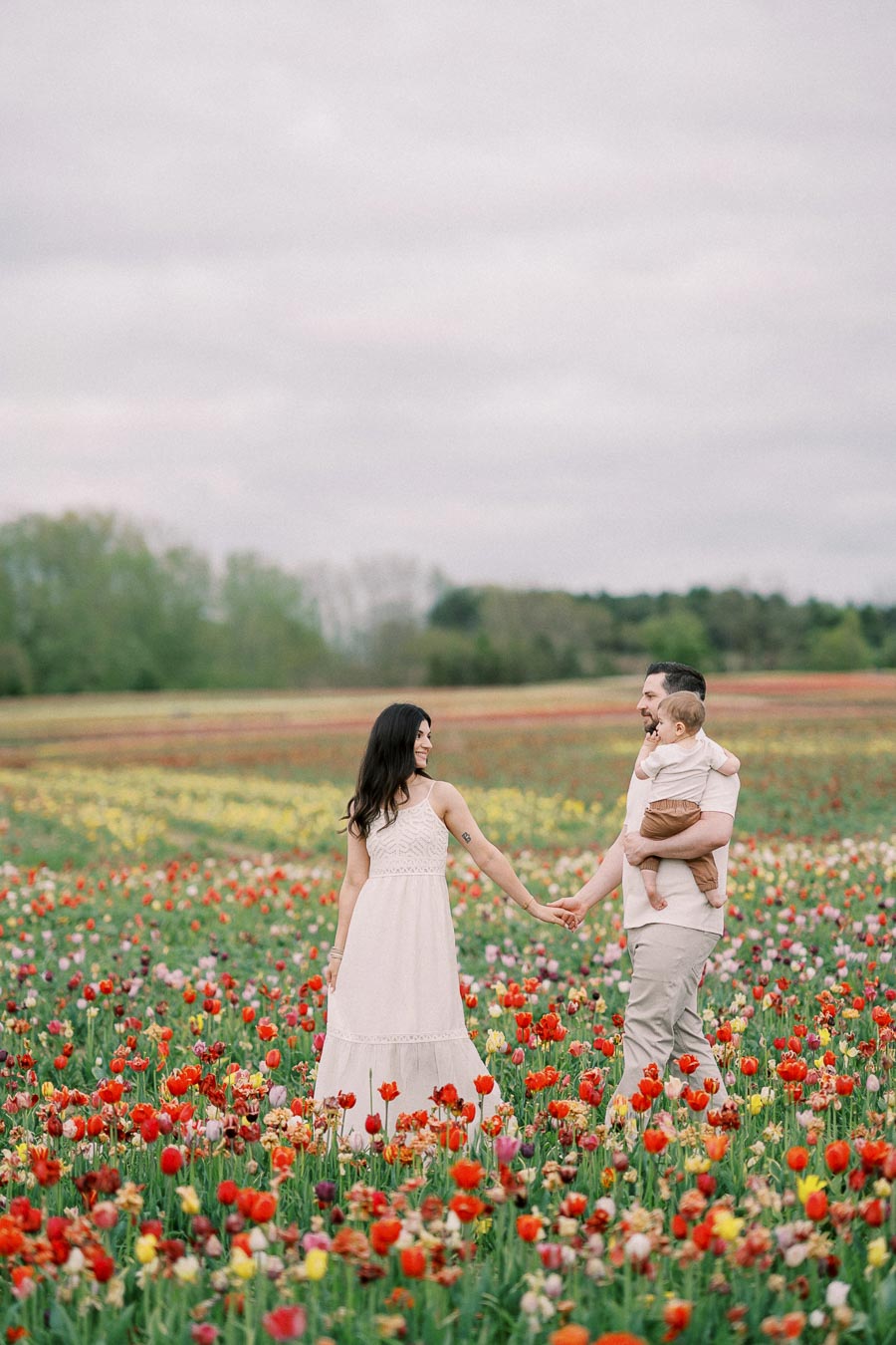 A family enjoys a day out in a vibrant tulip field, surrounded by colorful blooms.