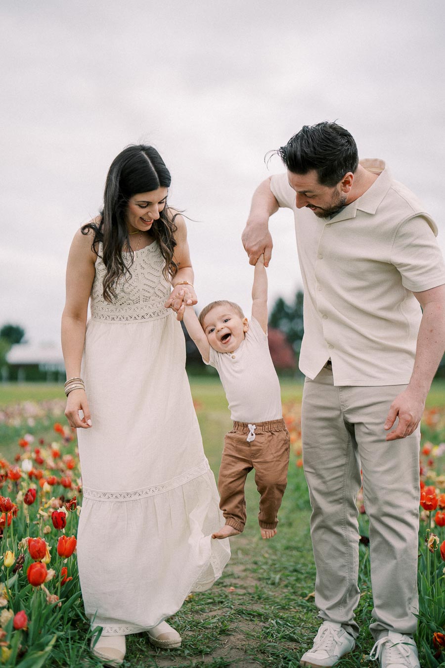 A joyful family moment captured in a vibrant tulip field, with parents playfully lifting their child.