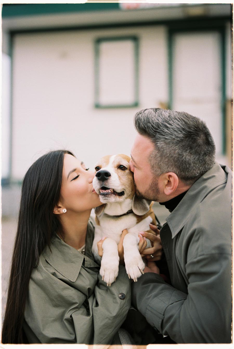 A couple lovingly kisses their beagle on both cheeks, capturing a moment of affection and joy.