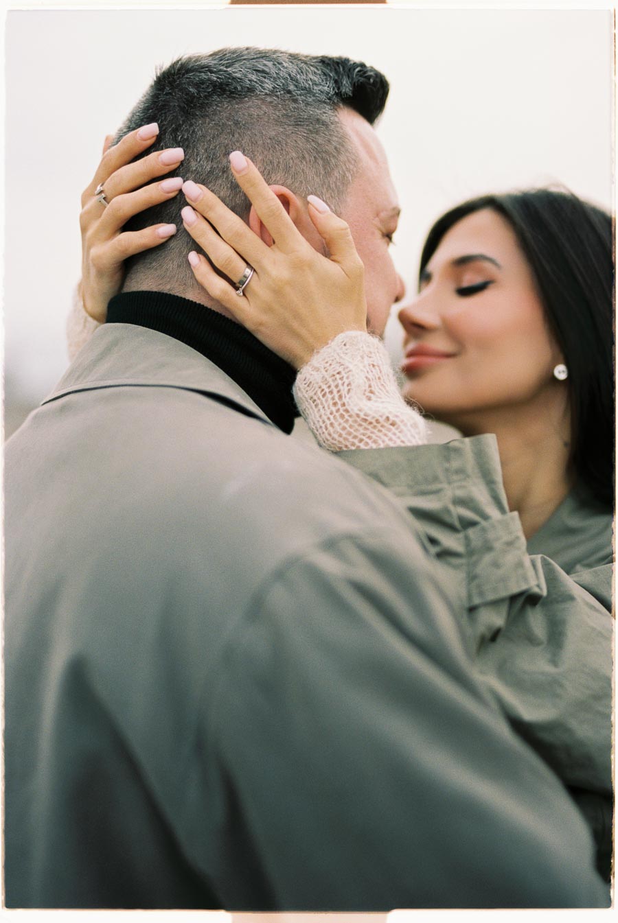 A tender moment captured between a couple, with the woman gently holding the man's face as they embrace closely.