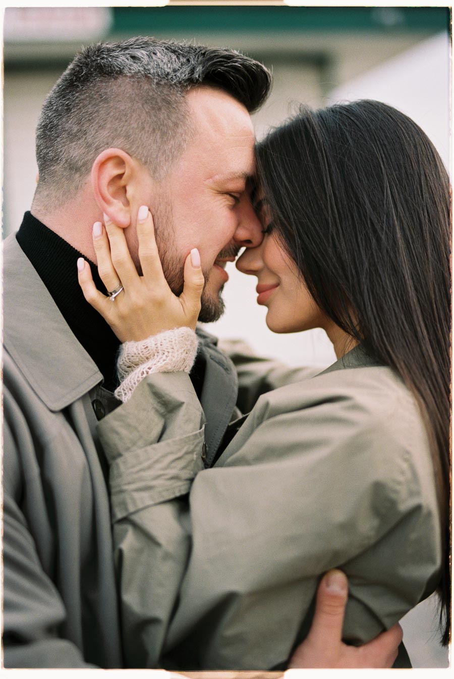 A couple shares an intimate moment, embracing closely with their foreheads touching.