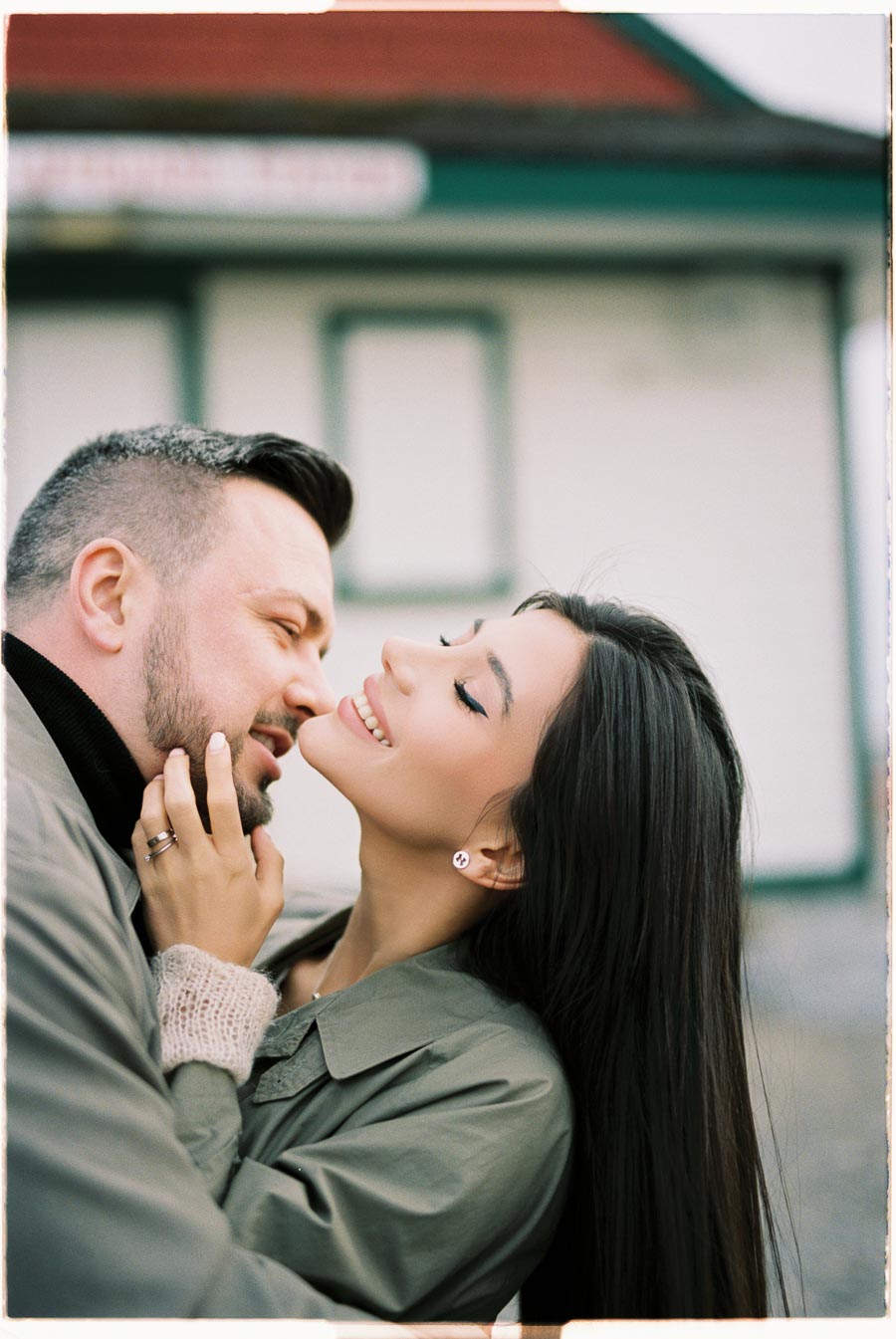 A couple shares a tender moment, smiling at each other in an outdoor setting.