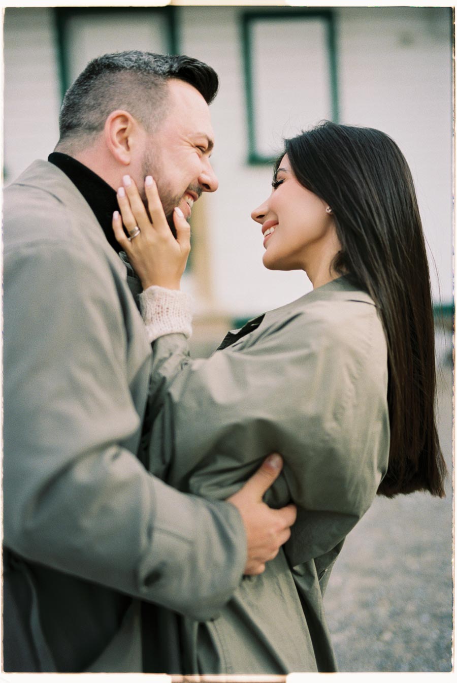 A couple shares a joyful moment, embracing and smiling at each other outdoors.