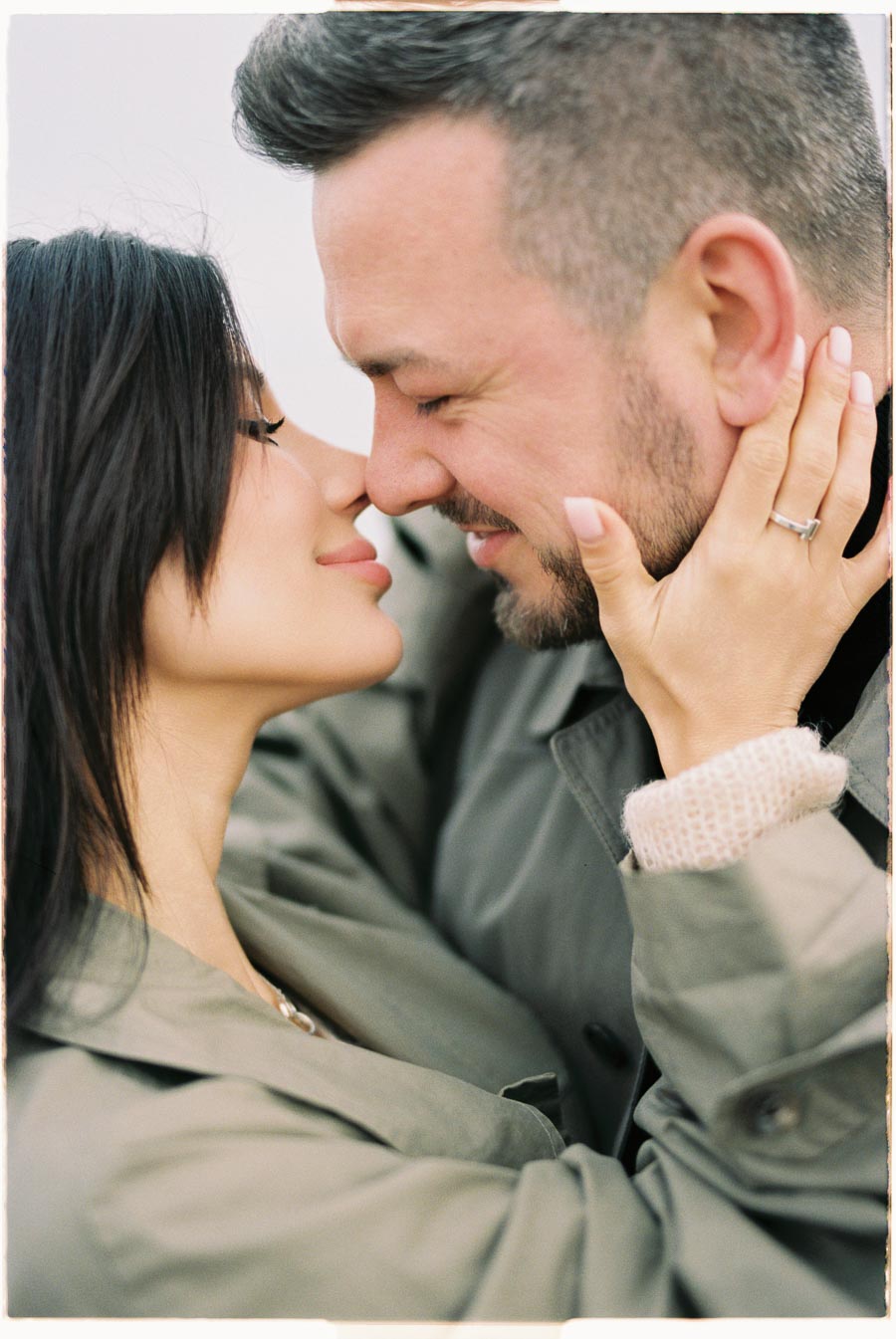 A couple shares an intimate moment, smiling with their noses touching, showcasing affection and closeness.