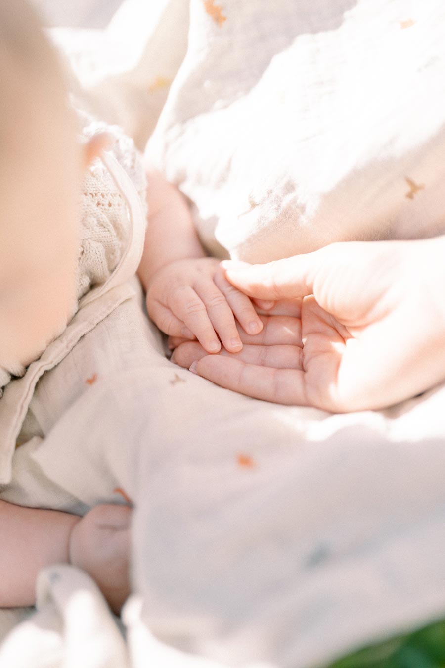 A tender moment captured between a baby and an adult, showcasing the baby's hand resting in the adult's palm.
