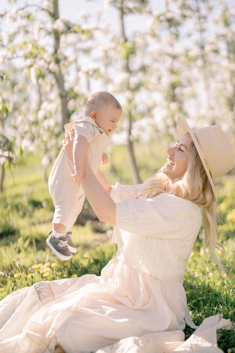 A joyful moment between a woman and a baby in a blooming orchard.