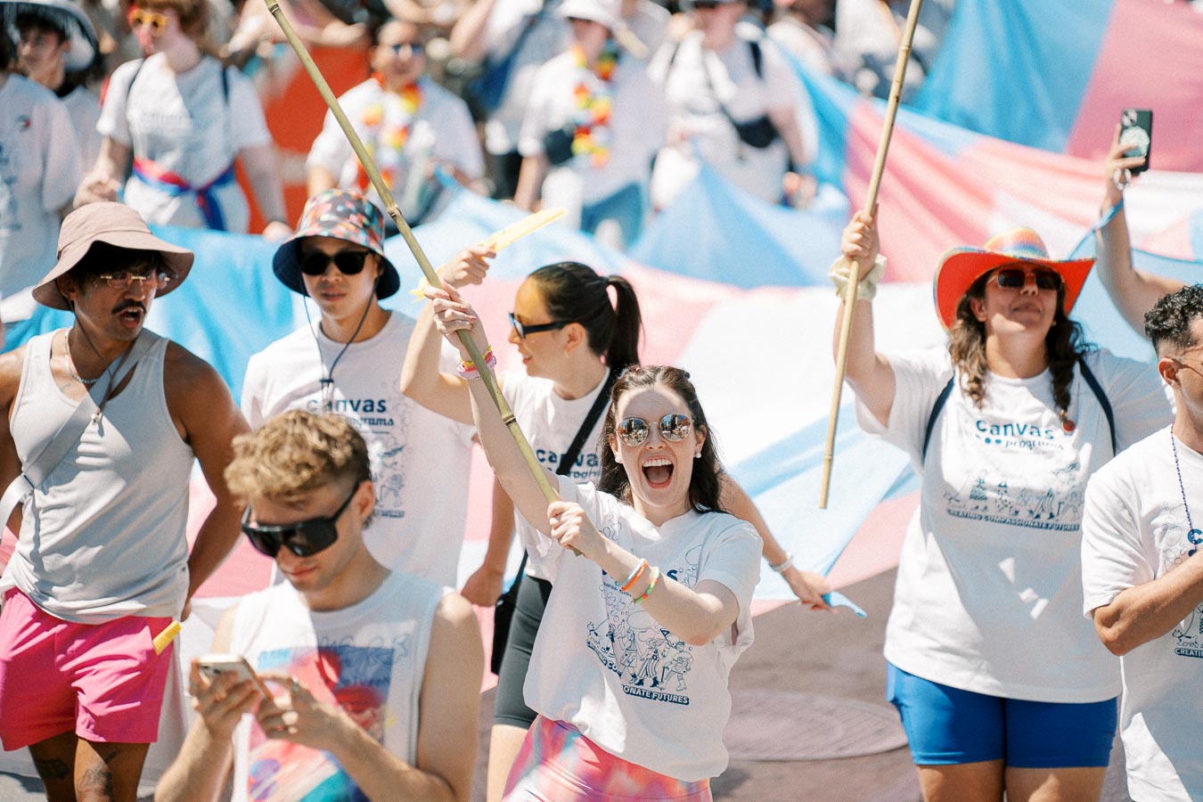 Participants in a pride parade joyfully carry a large transgender flag, celebrating diversity and inclusion.