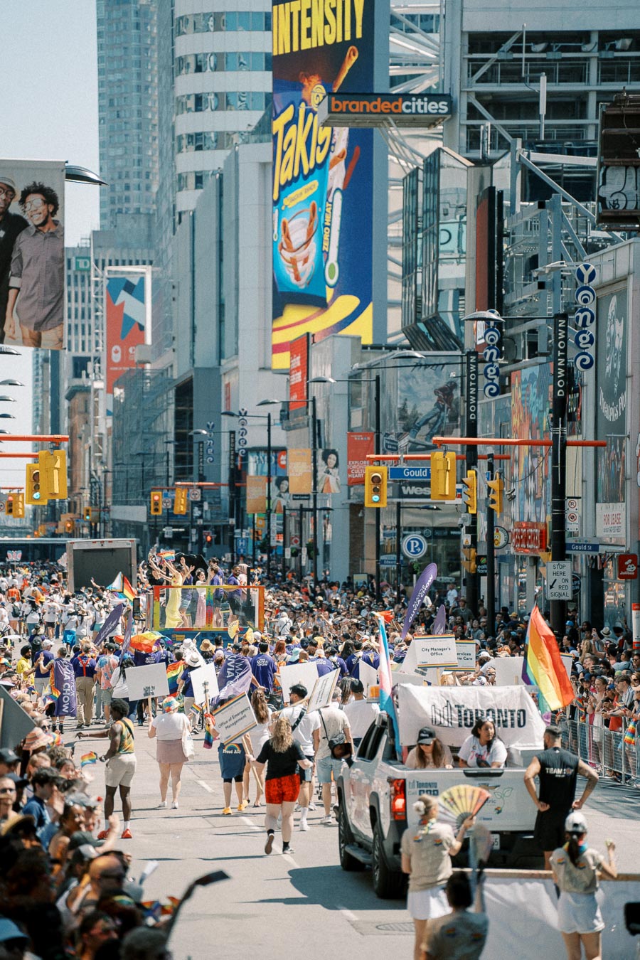 A lively parade in Toronto featuring participants with rainbow flags and banners, celebrating diversity and inclusion.