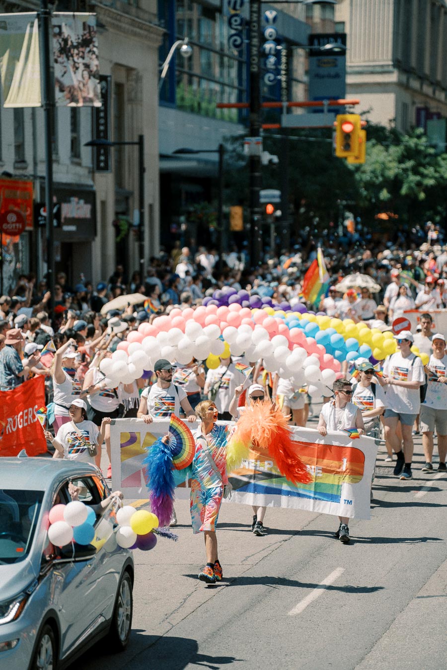 Participants march in a colorful pride parade, carrying rainbow flags and balloons, celebrating diversity and inclusion.