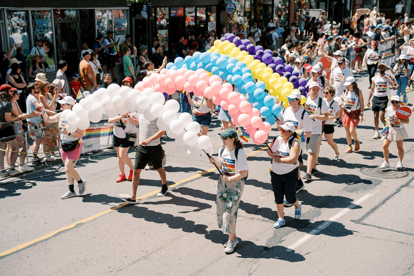 Participants in a pride parade carry a vibrant balloon rainbow, celebrating diversity and inclusion.