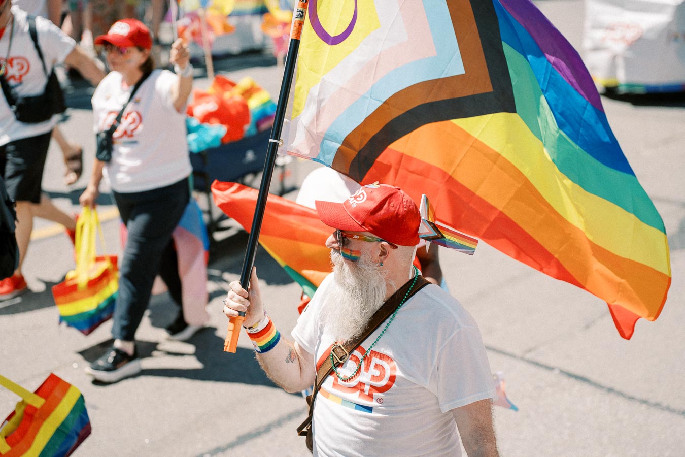 A participant in a pride parade holds a rainbow flag, celebrating diversity and inclusion.