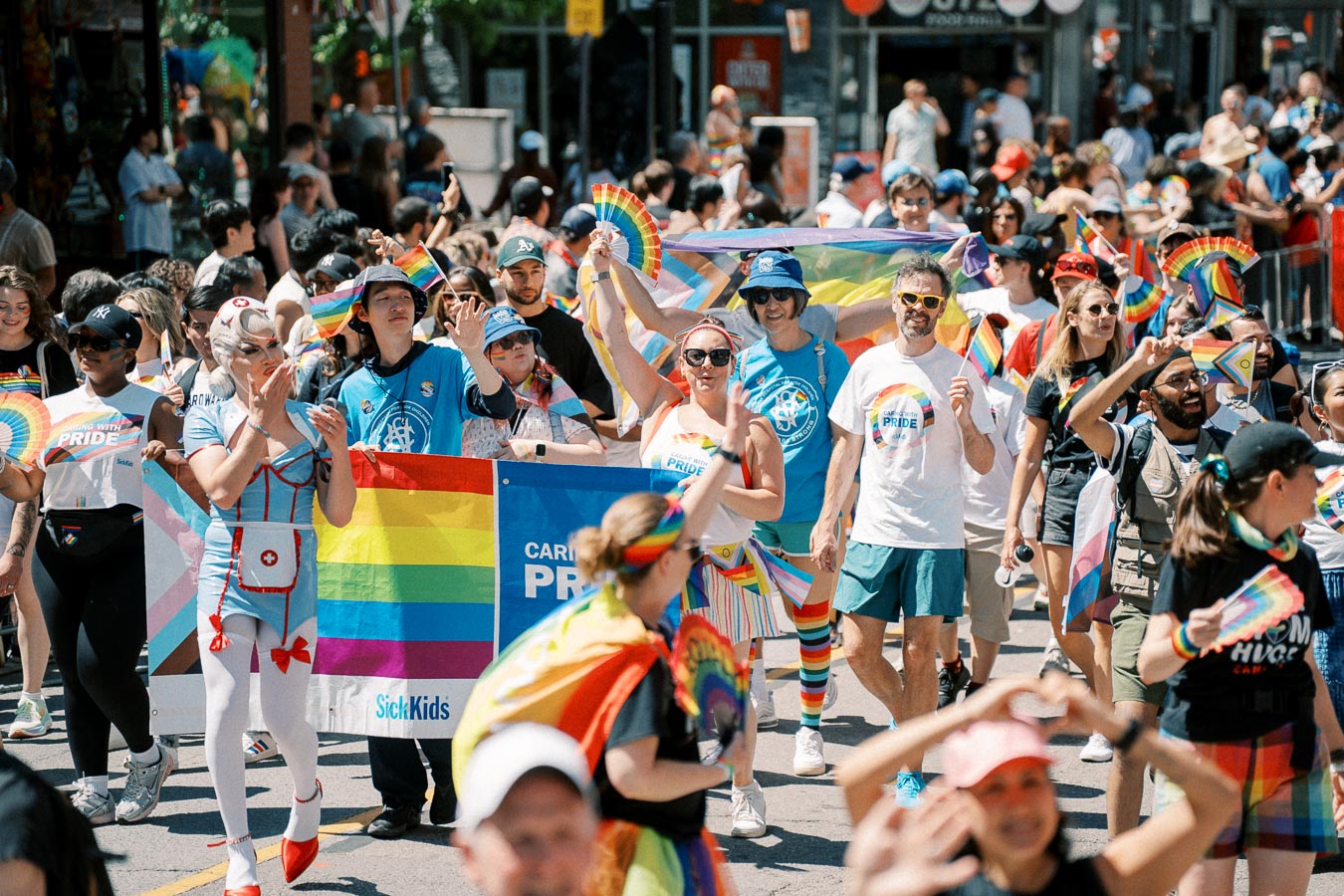 Participants celebrate diversity and inclusion at a vibrant Pride parade, waving rainbow flags and wearing colorful attire.