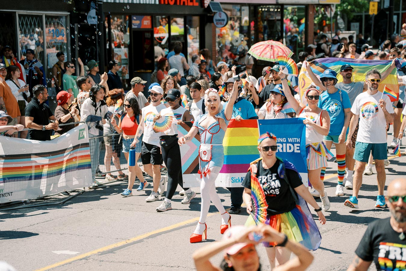 Participants celebrate at a Pride parade, showcasing colorful outfits and rainbow flags, embodying a spirit of inclusivity and joy.