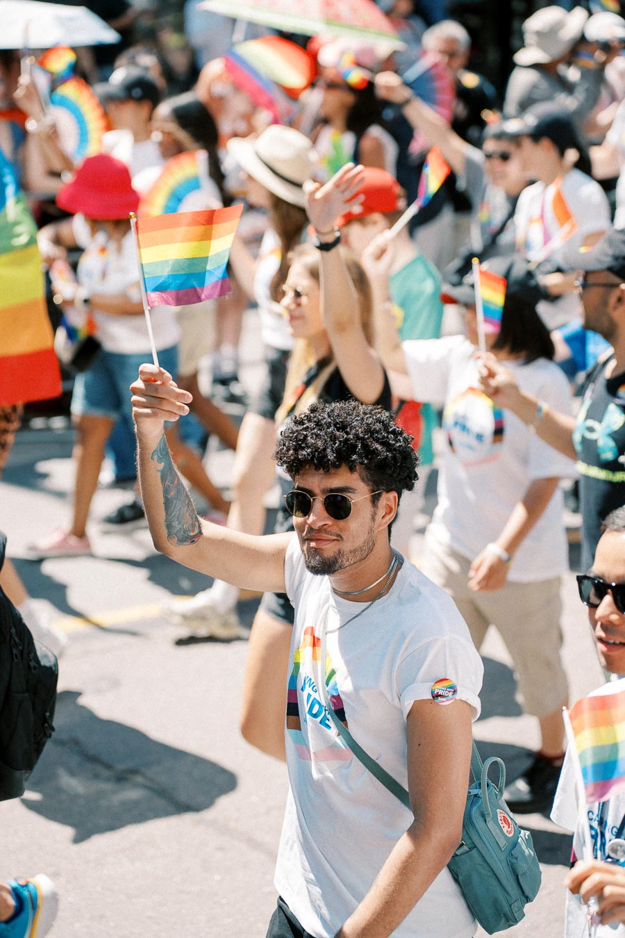 Participants in a pride parade celebrate with rainbow flags and vibrant clothing.