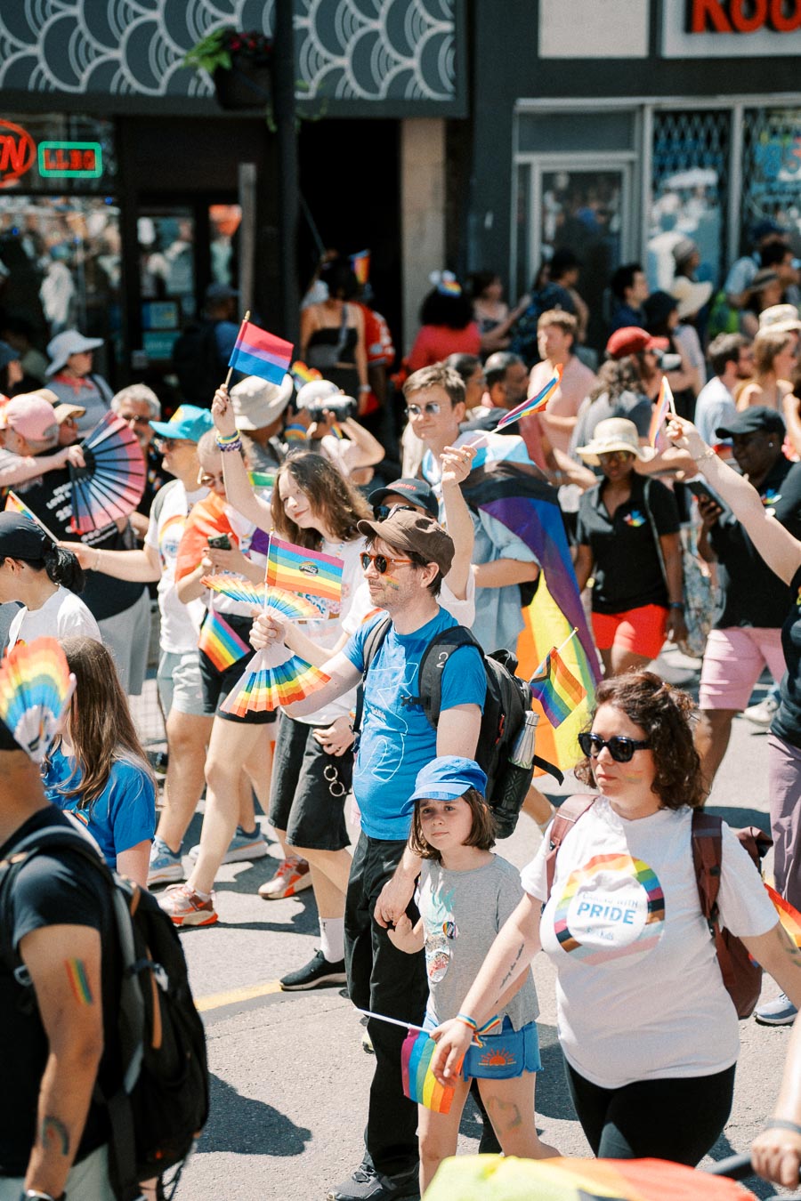 Participants in a Pride parade celebrate with rainbow flags and vibrant attire, showcasing support for the LGBTQ+ community.