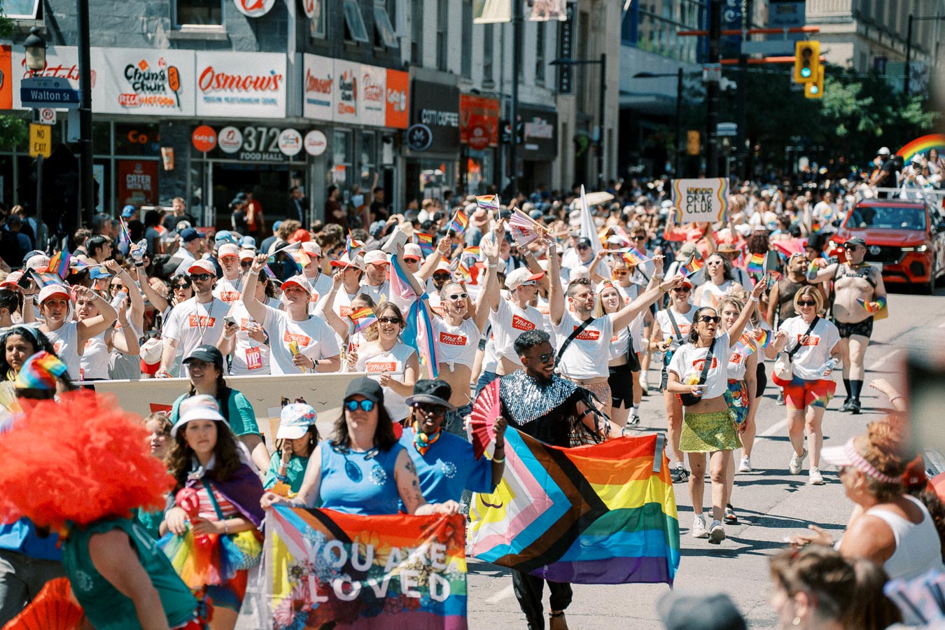 Participants in a vibrant pride parade march down a city street, waving rainbow flags and celebrating diversity.
