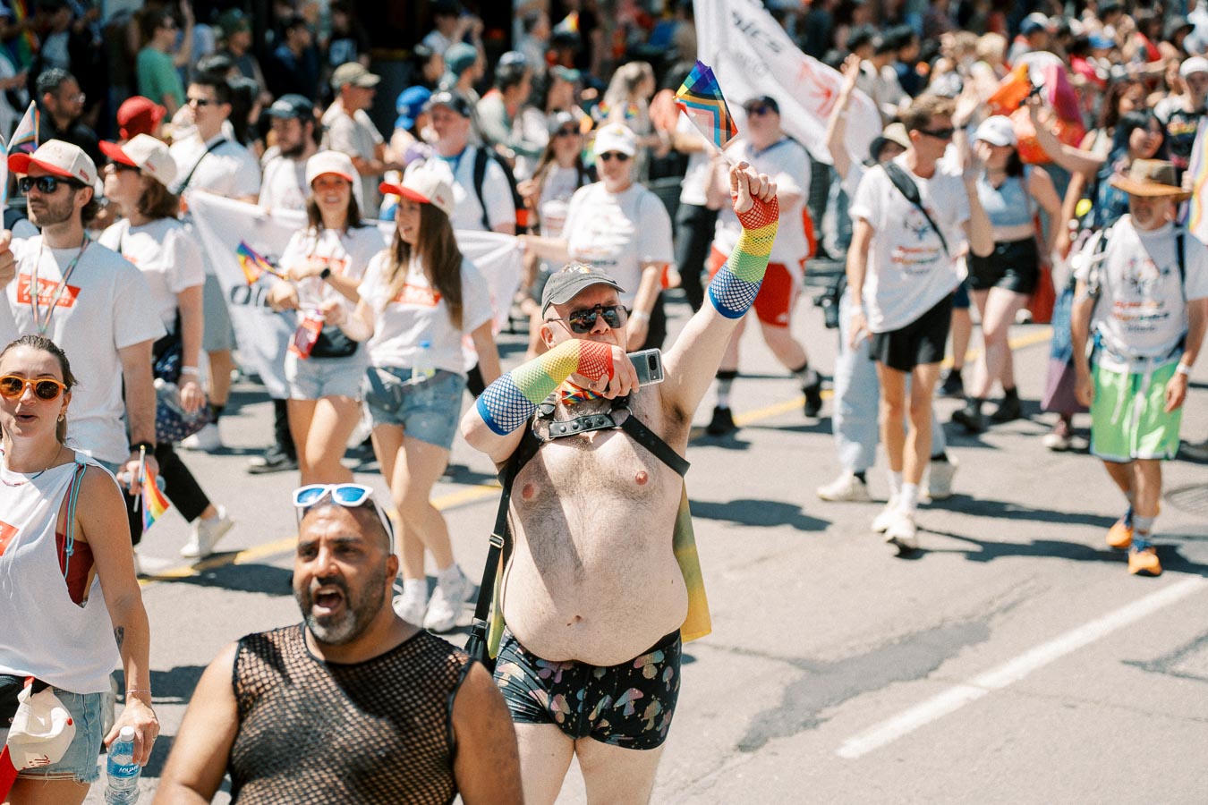 Participants in a pride parade celebrate with colorful outfits and rainbow flags, showcasing diversity and inclusion.