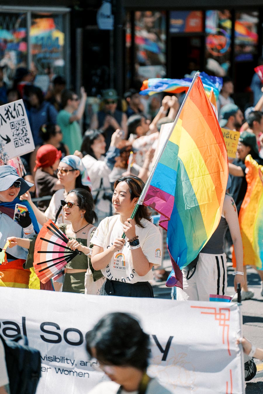 Participants in a pride parade hold a rainbow flag and signs, celebrating diversity and inclusion.