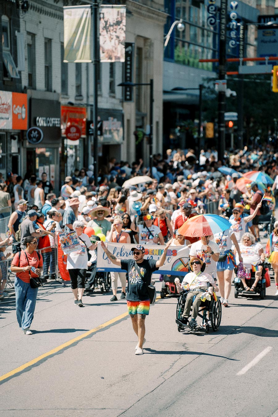 A vibrant Pride parade with participants holding rainbow umbrellas and banners, celebrating diversity and inclusion on a bustling city street.