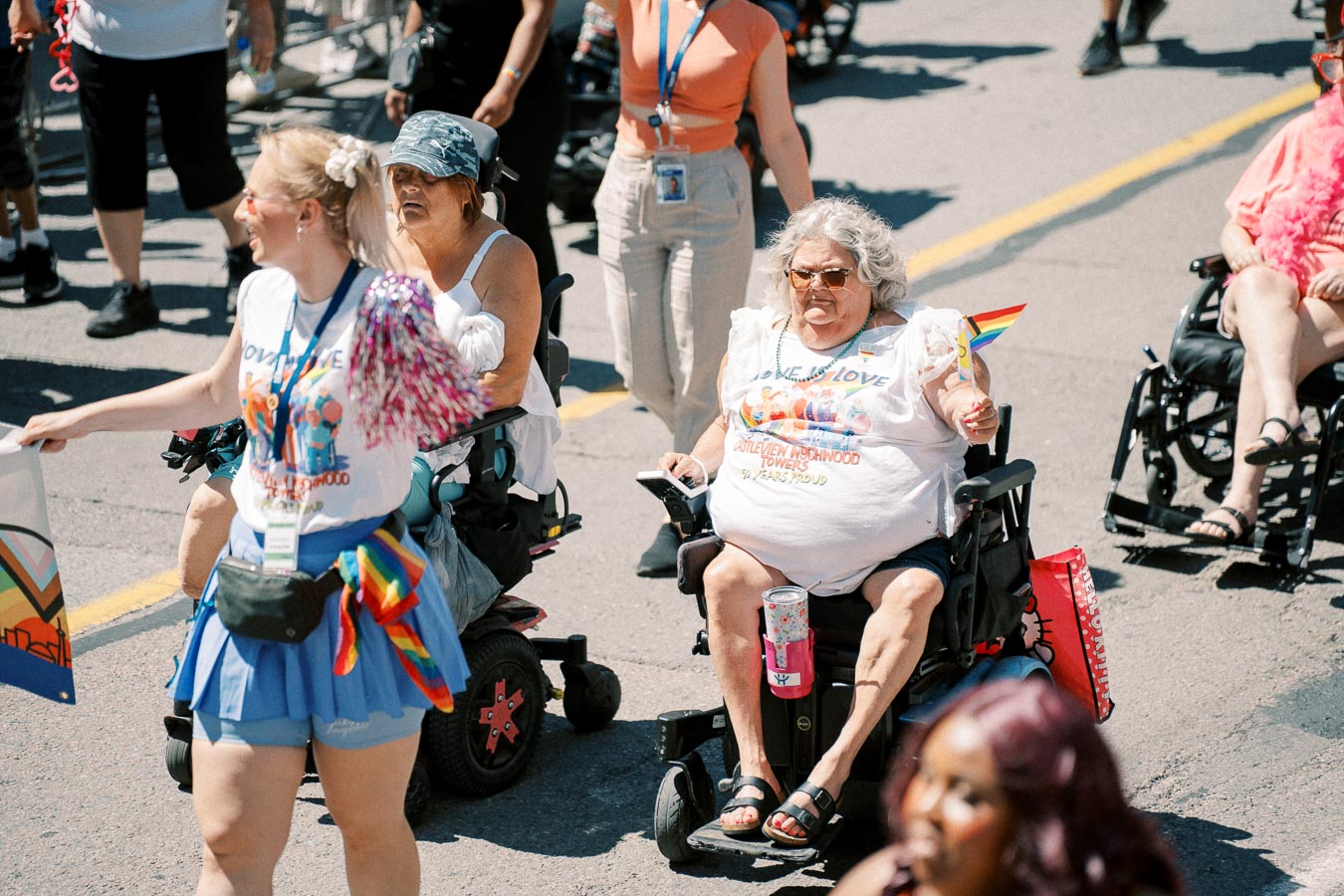 Participants in a parade celebrate with rainbow flags and colorful attire, promoting inclusivity and diversity.