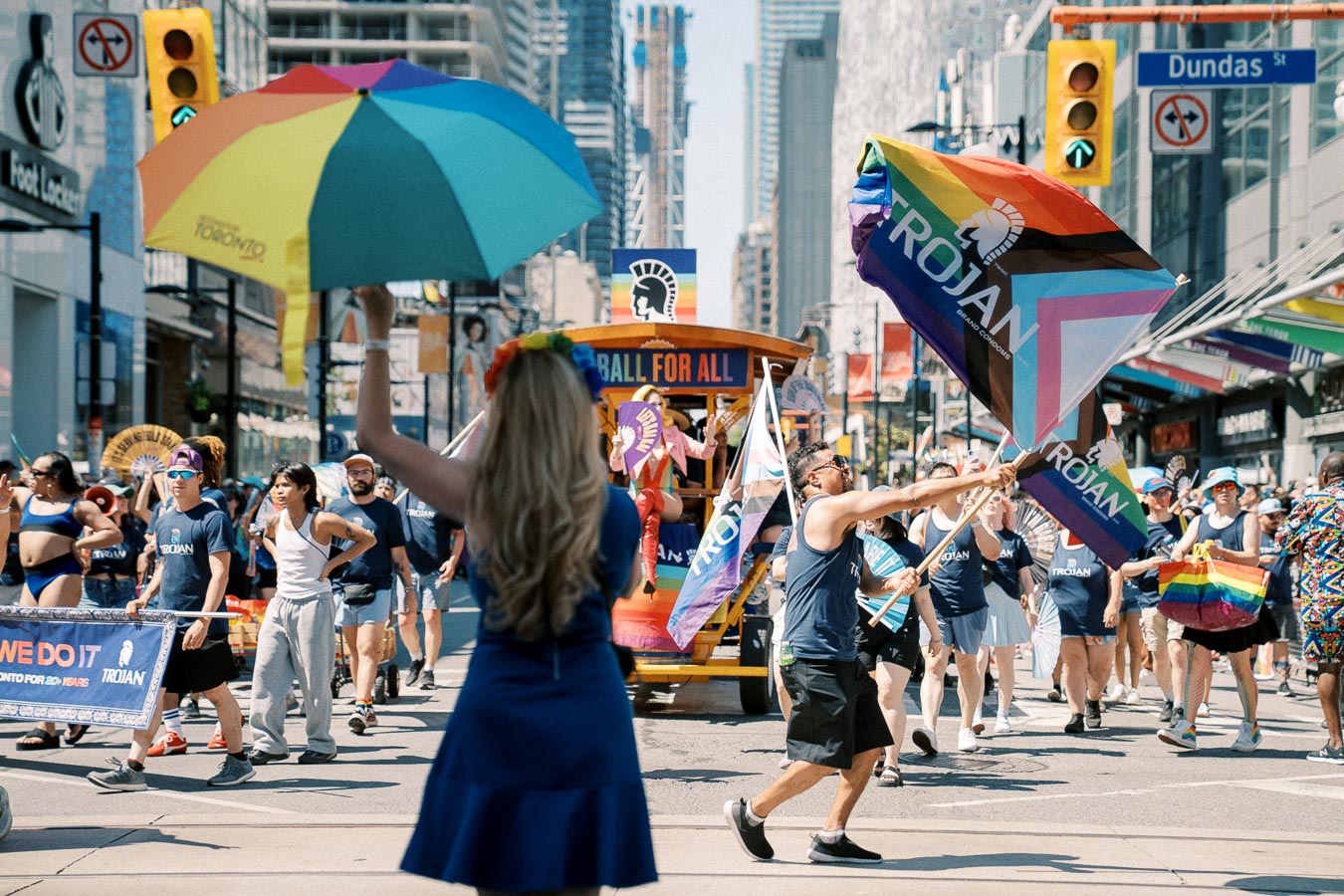 Participants in a pride parade on Dundas Street, Toronto, celebrate with rainbow flags and banners, promoting inclusivity and diversity.