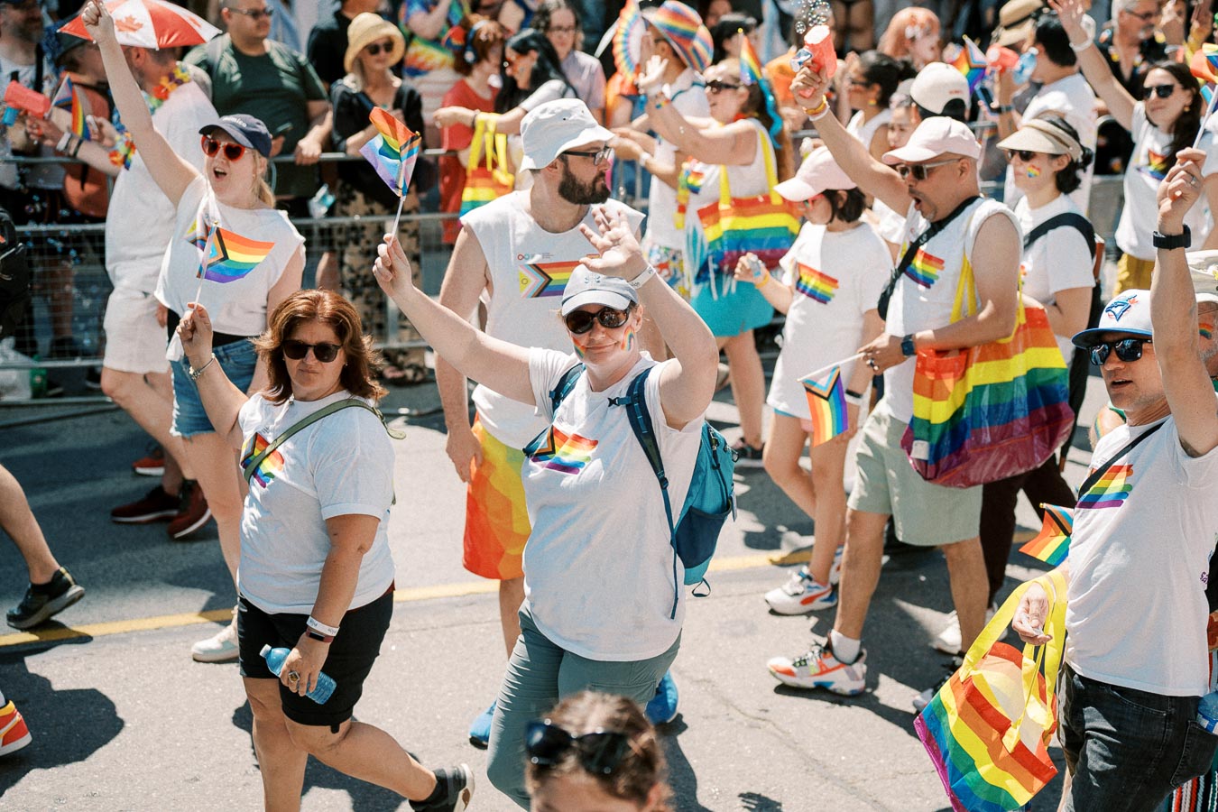 Participants in a pride parade celebrate with rainbow flags and themed attire, showcasing support for the LGBTQ+ community.