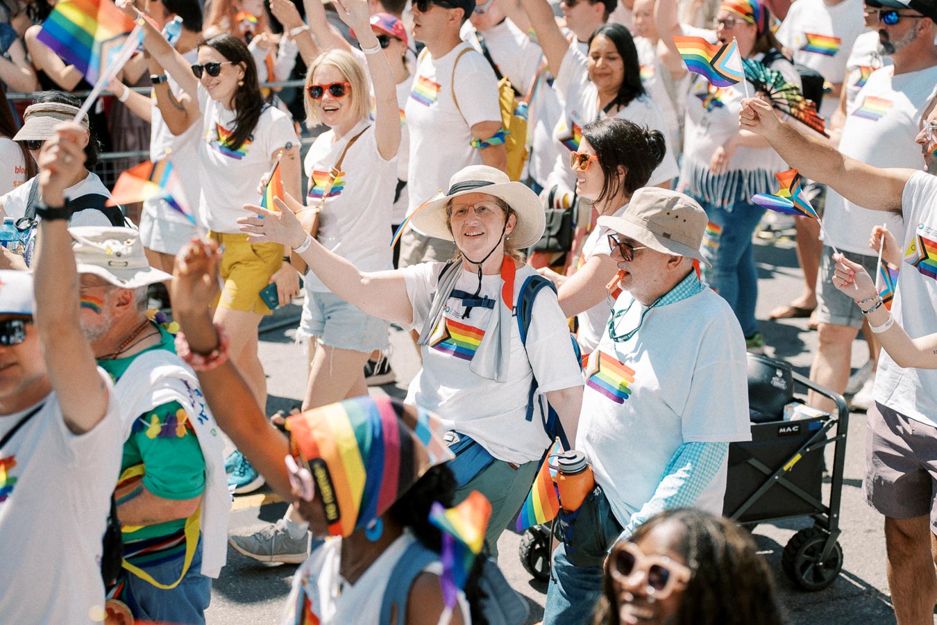 Participants in a pride parade celebrate with rainbow flags and festive attire.