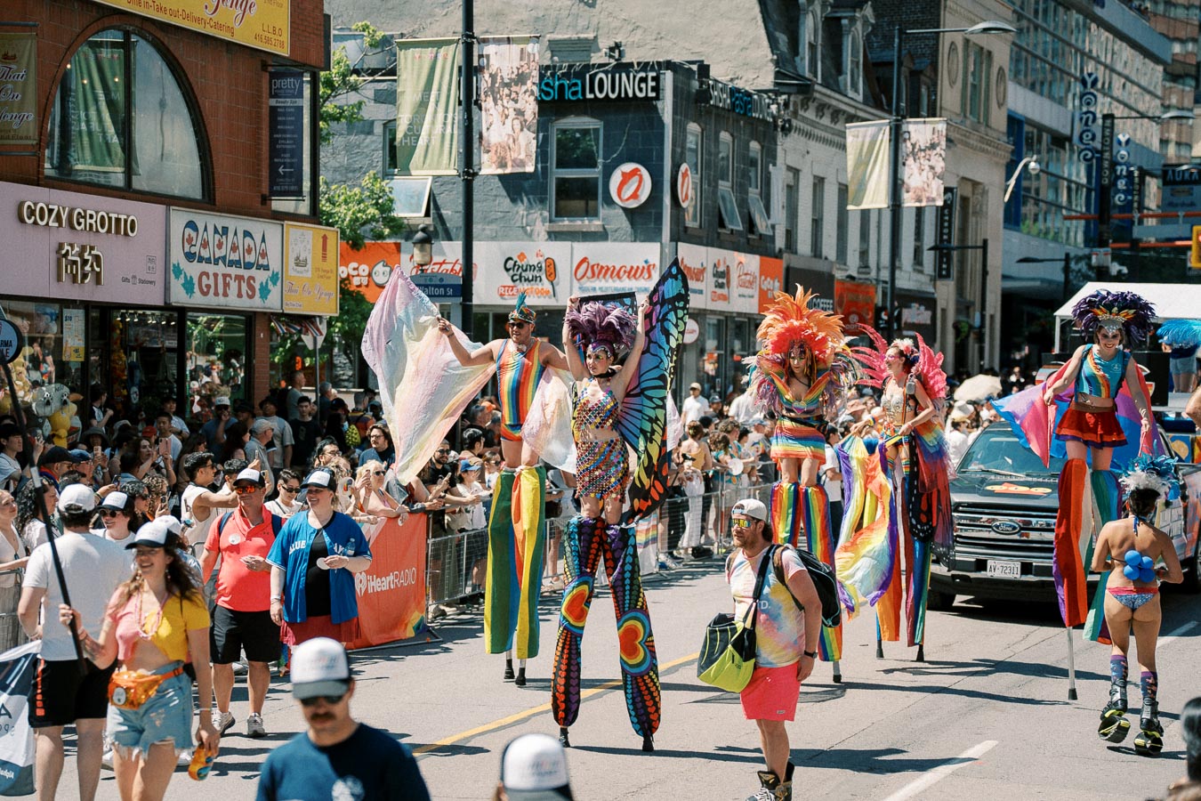A lively parade featuring participants in colorful costumes and stilts, celebrating on a bustling city street.