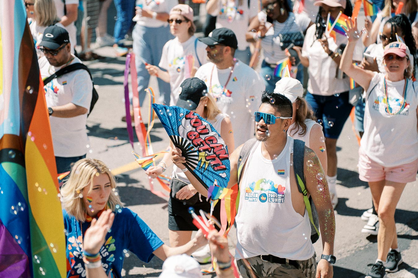 Participants in a pride parade celebrate with colorful attire and rainbow flags, embodying unity and diversity.