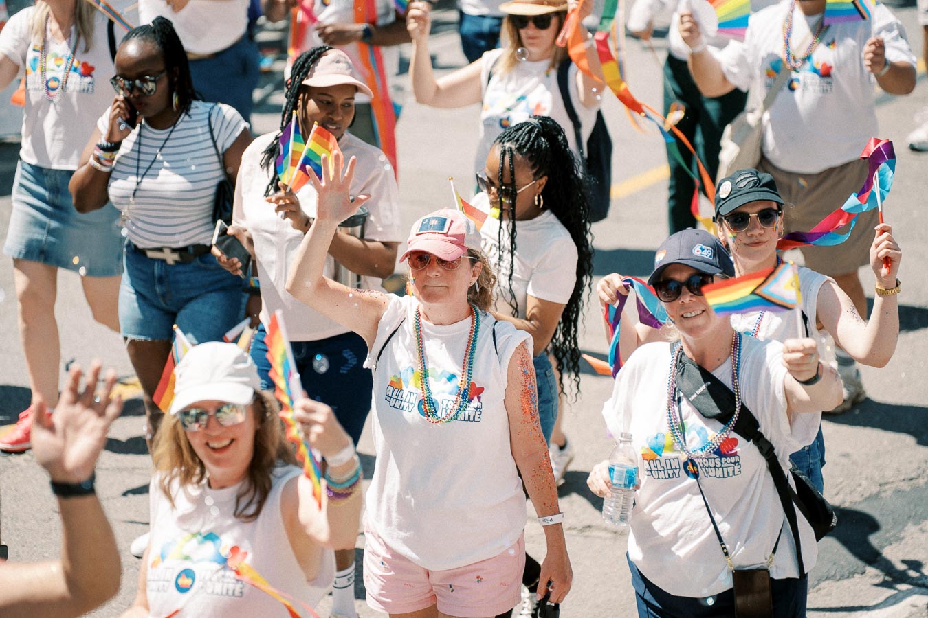 Participants at a pride parade celebrate with rainbow flags and festive attire, promoting unity and inclusivity.