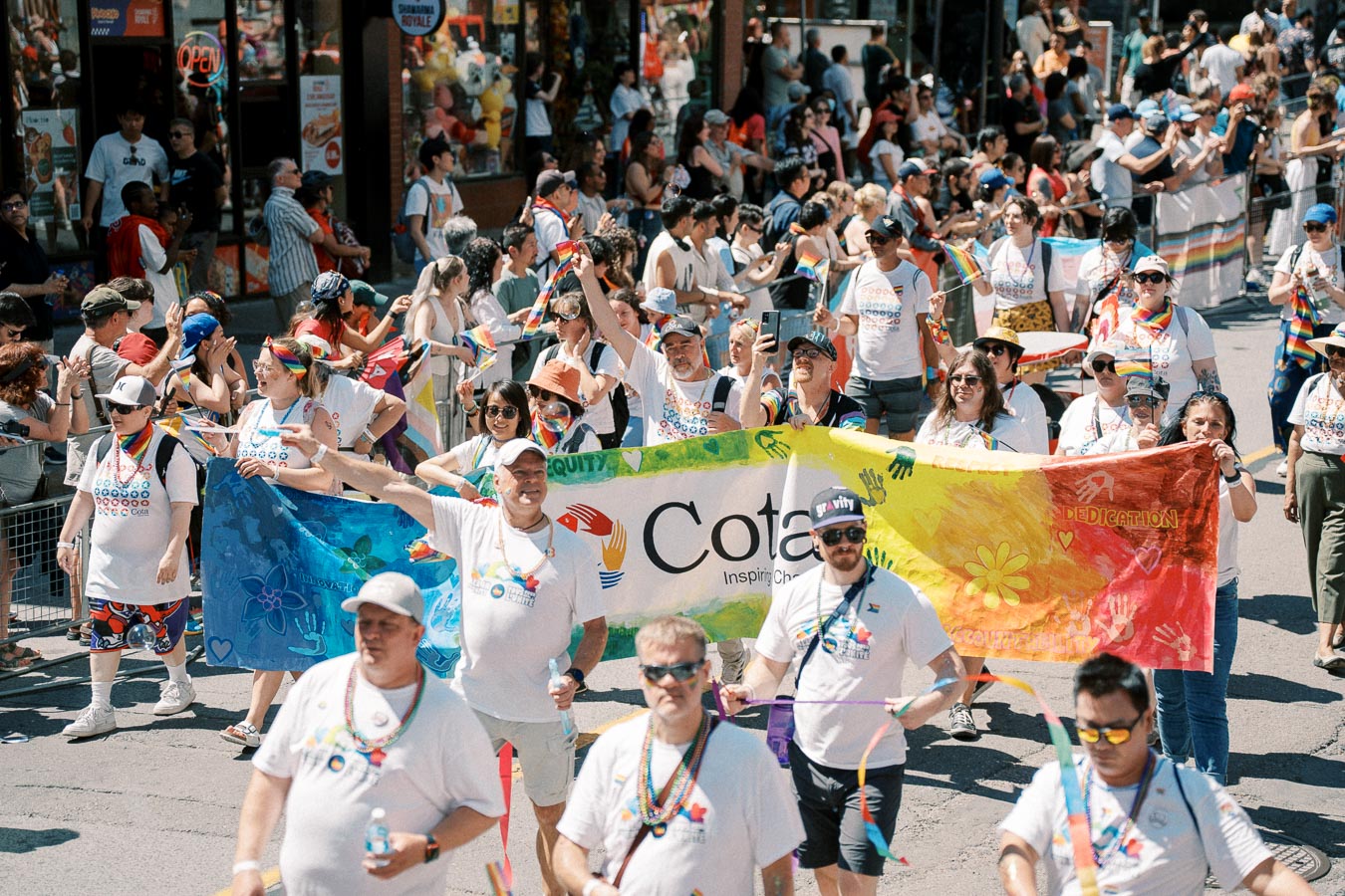 Participants in a pride parade march with a colorful banner and rainbow flags, celebrating diversity and inclusion.
