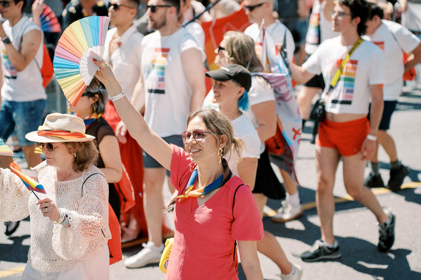 Participants in a pride parade celebrate with colorful attire and rainbow-themed accessories, showcasing support for LGBTQ+ rights.
