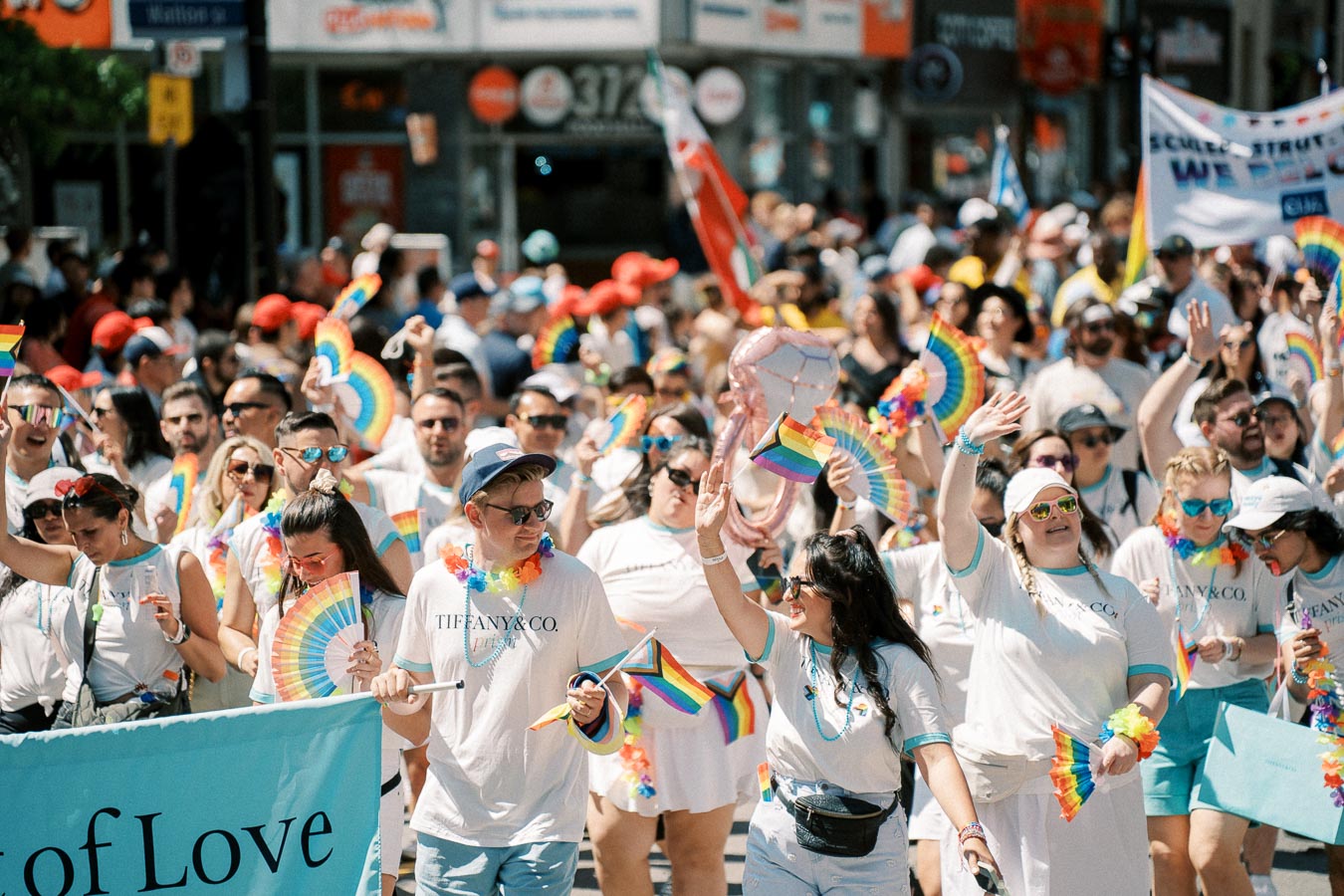 Participants in a pride parade celebrate with rainbow flags and accessories, showcasing support for LGBTQ+ rights.