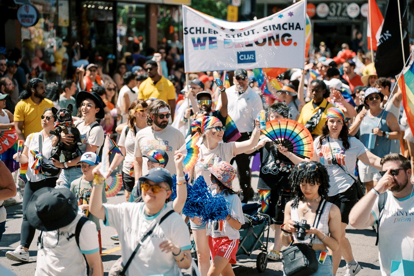 Participants celebrate at a pride parade, showcasing vibrant rainbow flags and banners, embodying a spirit of inclusivity and joy.