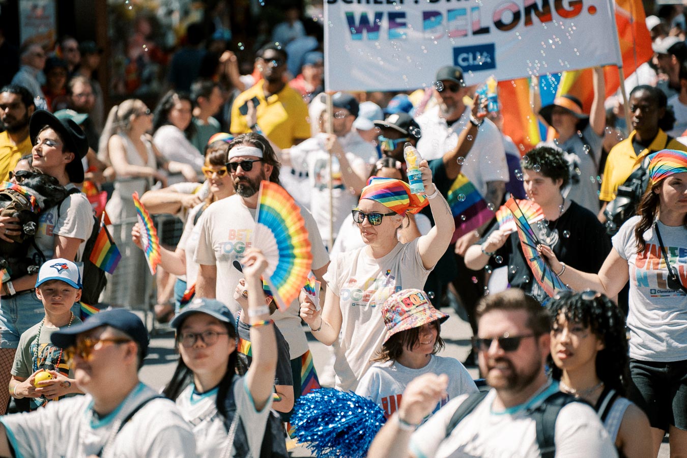 Participants at a pride parade celebrate with rainbow flags and colorful attire, embodying a spirit of inclusivity and joy.