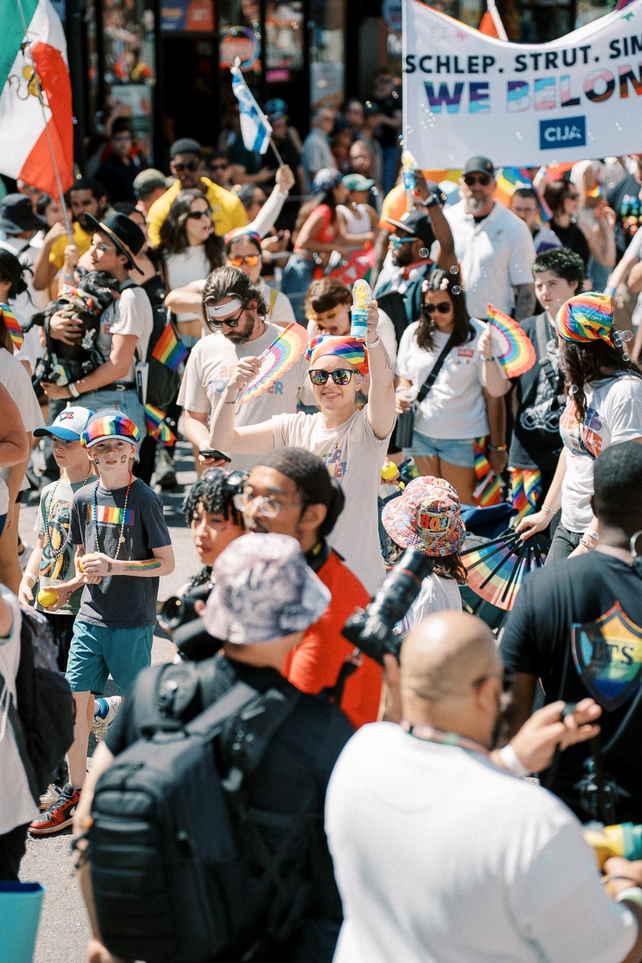 Participants at a pride parade celebrate with rainbow flags and accessories, promoting inclusivity and belonging.