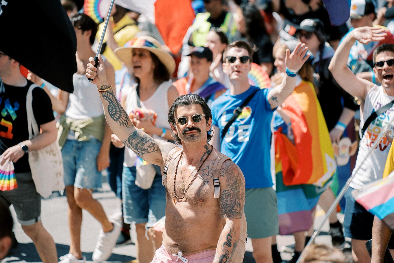 Participants celebrate at a pride parade, showcasing vibrant flags and diverse expressions of identity.